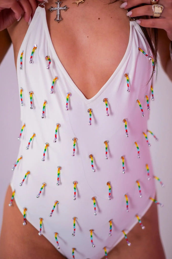 Detailed front close-up of White Beaded Swim Bodysuit highlighting rainbow beaded embellishments on white fabric for rave fashion.