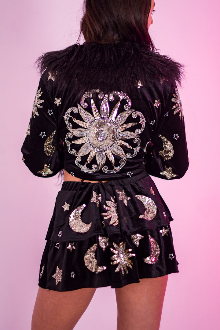 Back view of The Phase Cropped Jacket showcasing large sequin sun design and matching celestial skirt, ideal for festival fashion.
