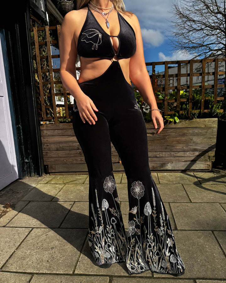 Model outdoors in The Fairy Garden Catsuit, highlighting silver floral embroidery on flared legs. Alternative velvet catsuit for festivals.
