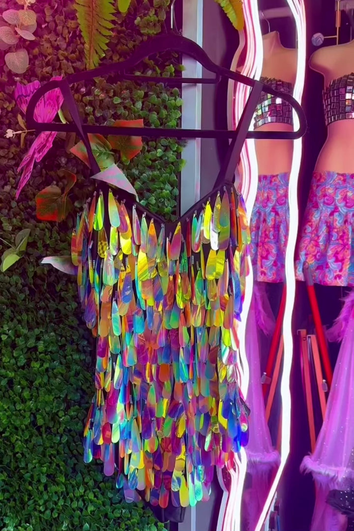 Angel Dust Bodysuit on hanger in boutique setting, displaying iridescent purple sequin design and fitted bra structure.