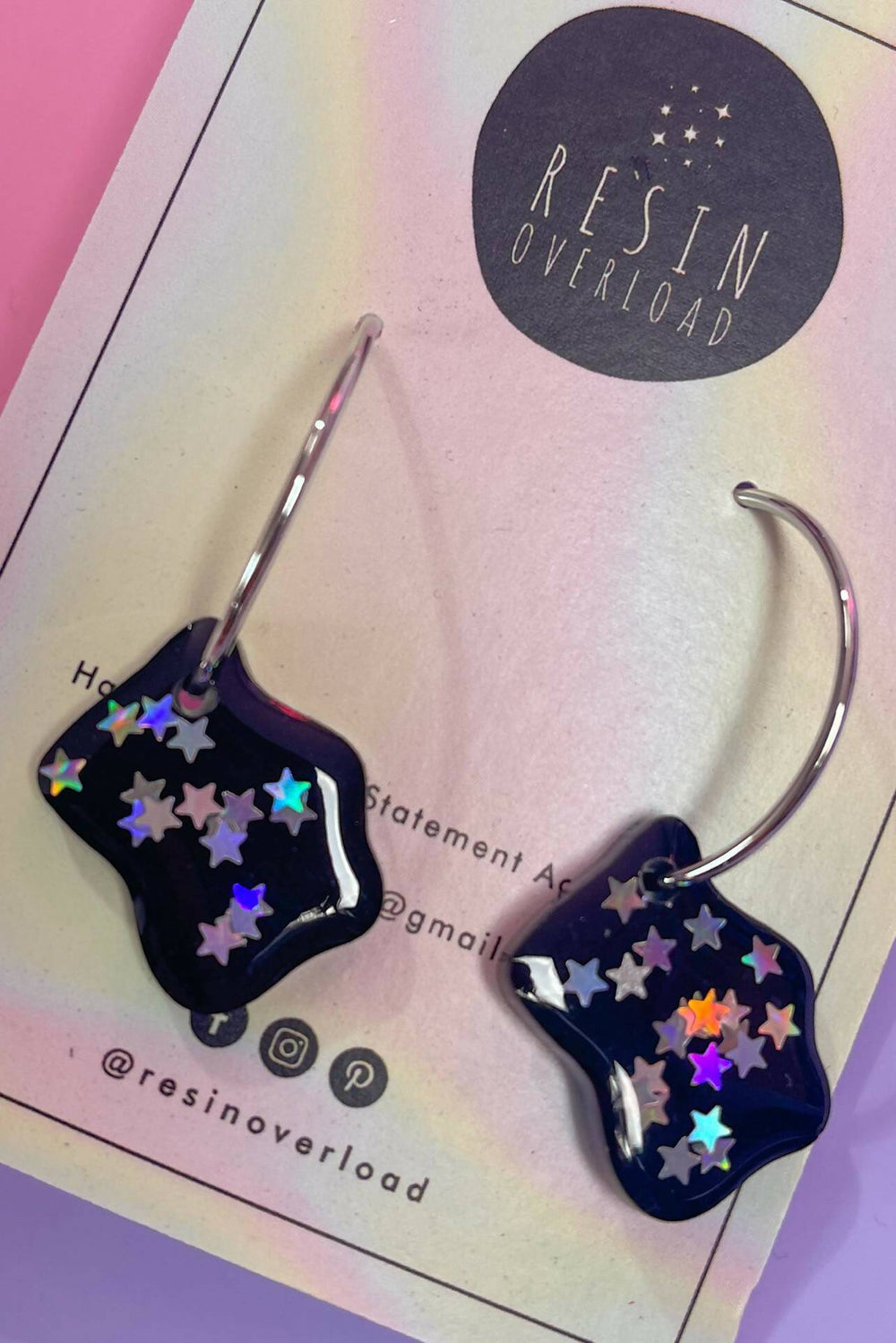 Close-up of resin earrings with silver hoops and star details