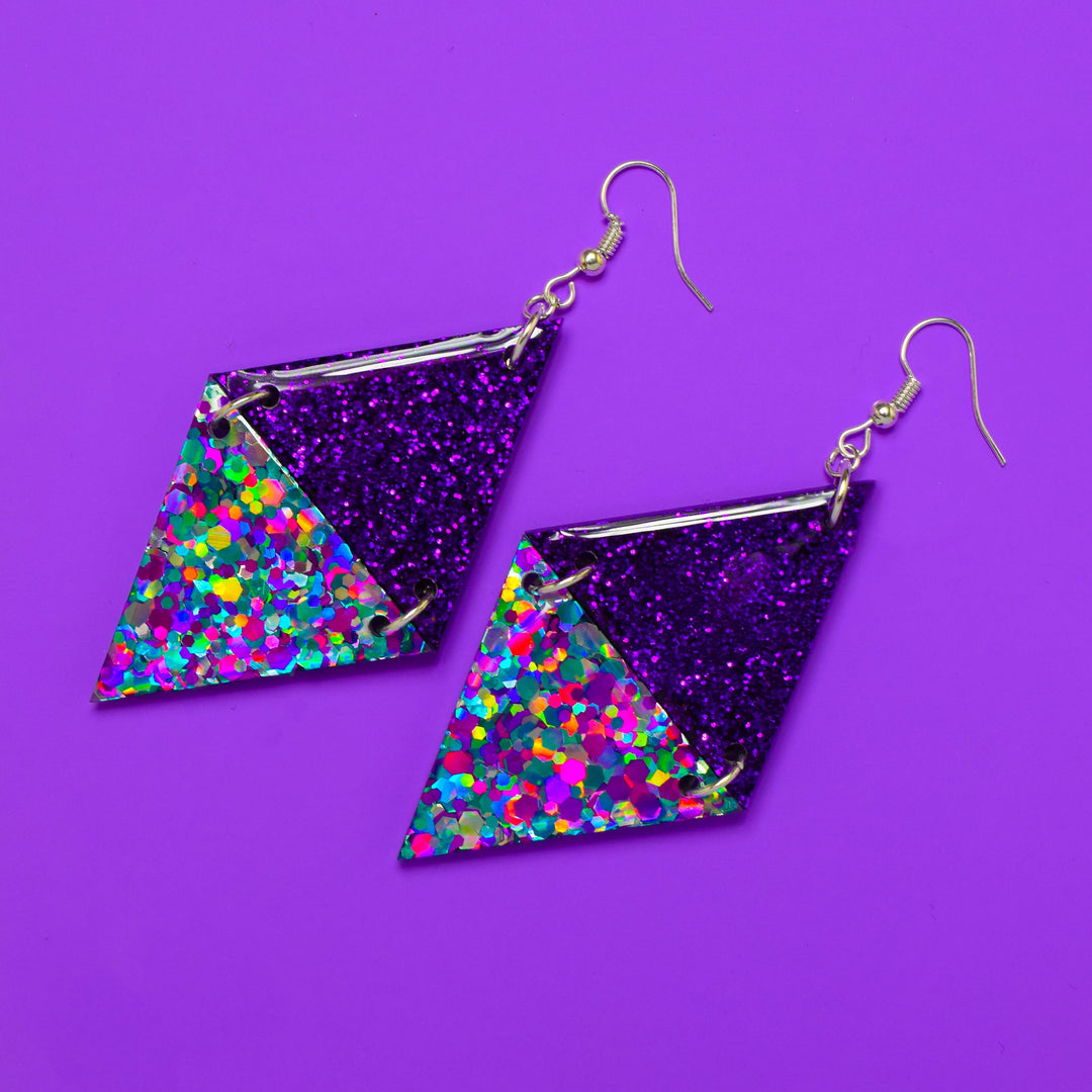 Purple glitter triangle earrings with rainbow resin on purple background