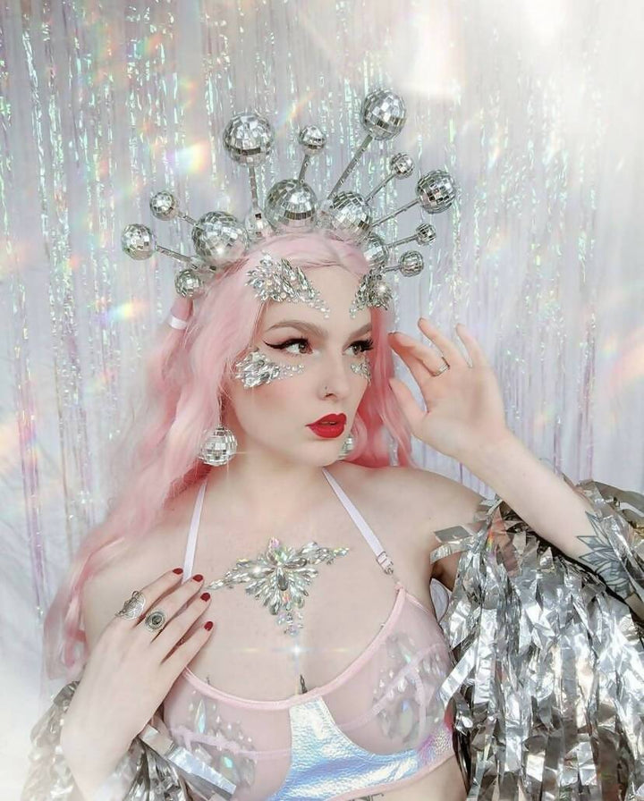 Model with pink hair wearing disco ball crown and sequin top.