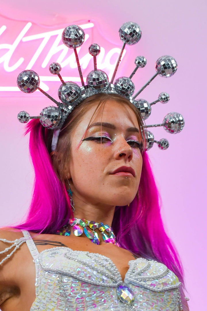 Disco ball crown headdress with pink hair and glitter makeup.