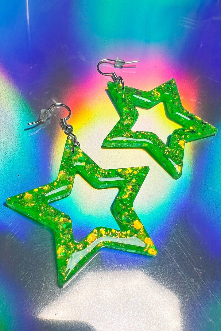 Neon lime green star earrings with glitter on rainbow background