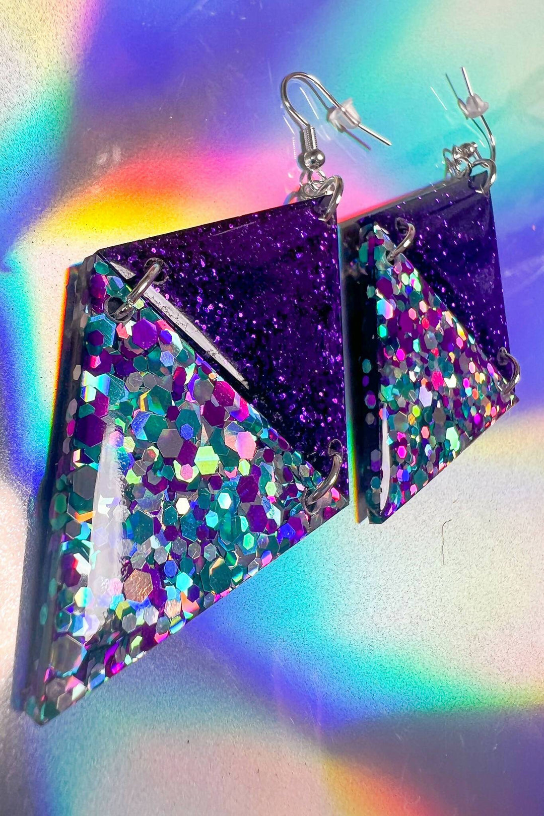 Side view of purple glitter triangle earrings with rainbow resin