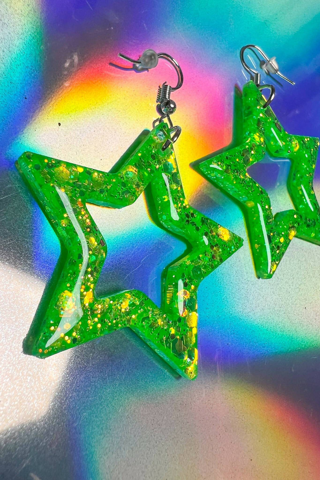 Close-up of lime green star earrings with iridescent glitter