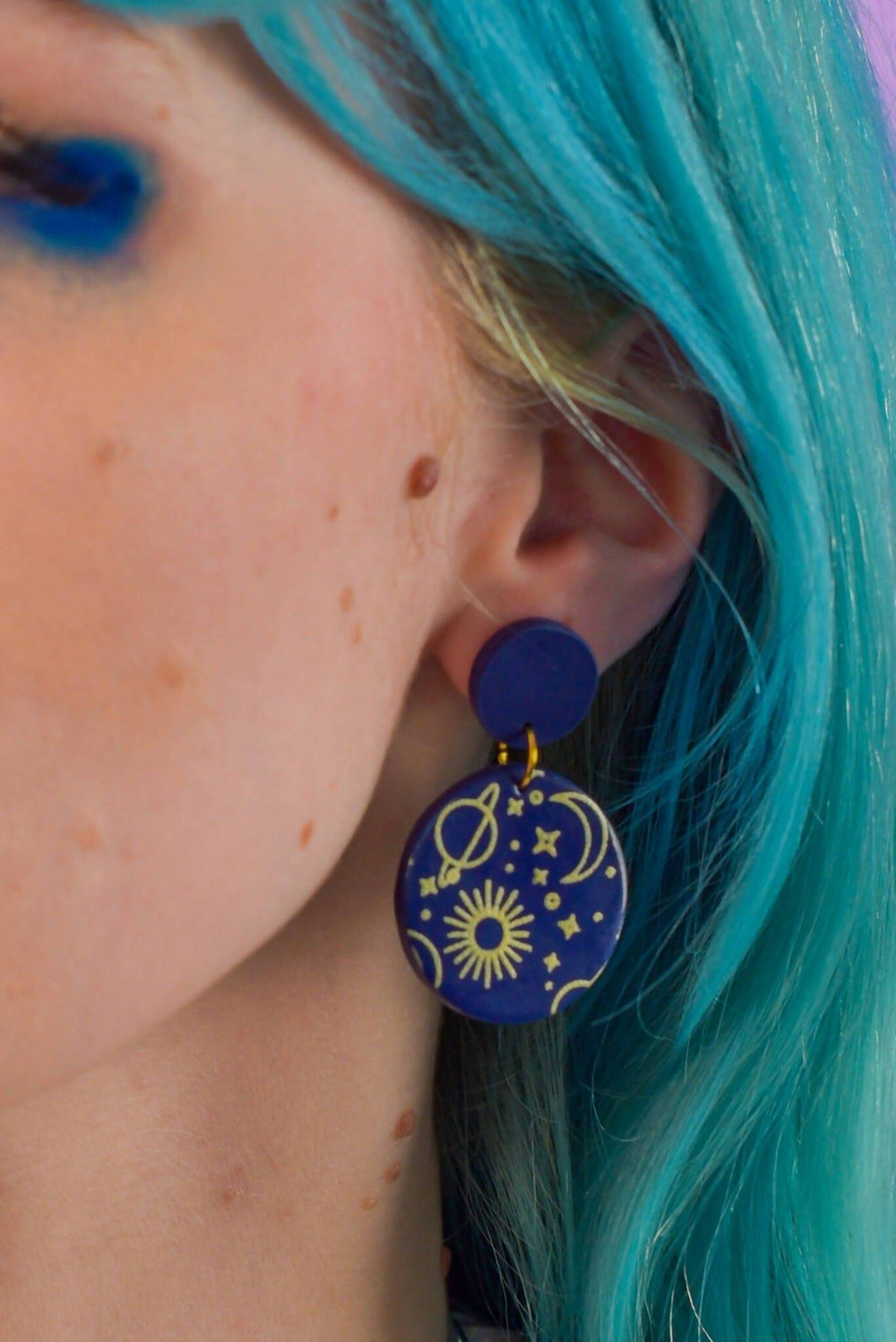 Close-up of space-themed earring with stars and planets