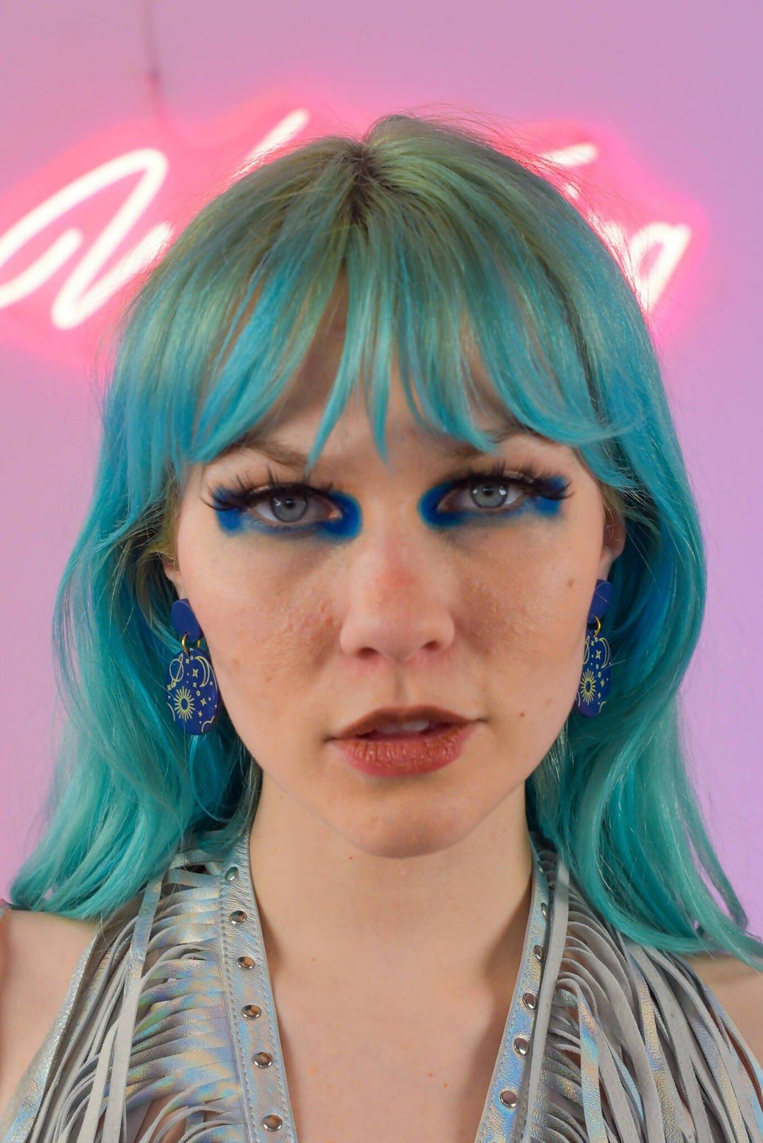 Model wearing blue space-themed dangle earrings