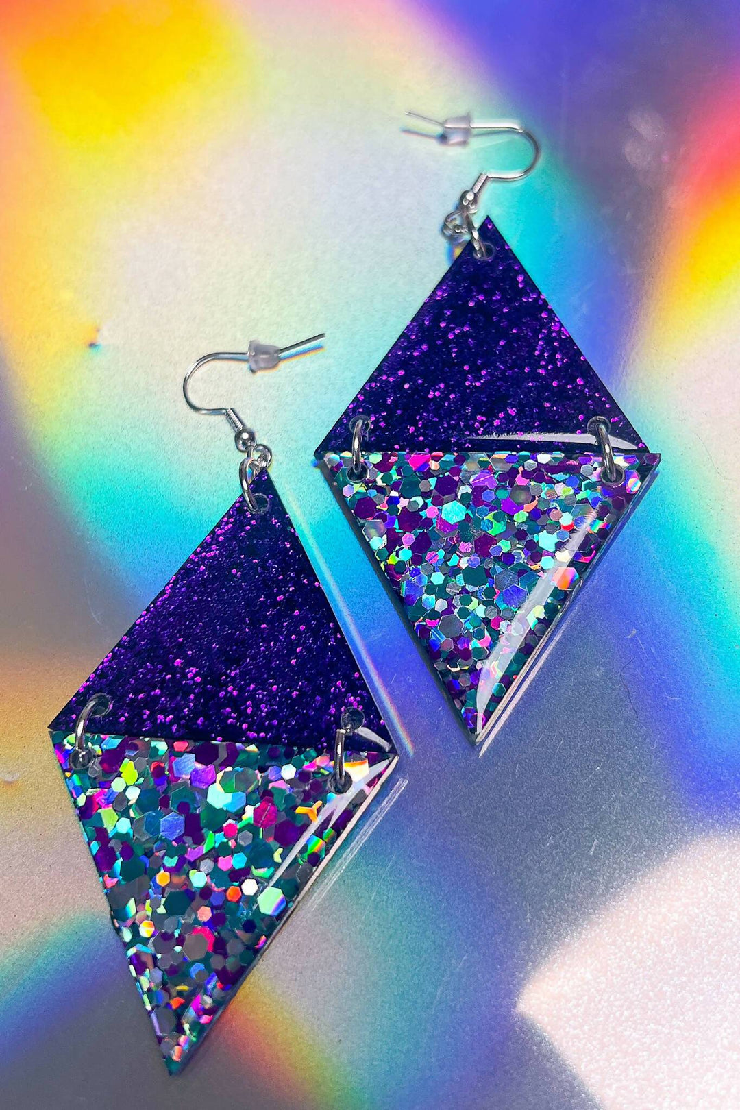 Purple glitter triangle earrings with rainbow resin on holographic background