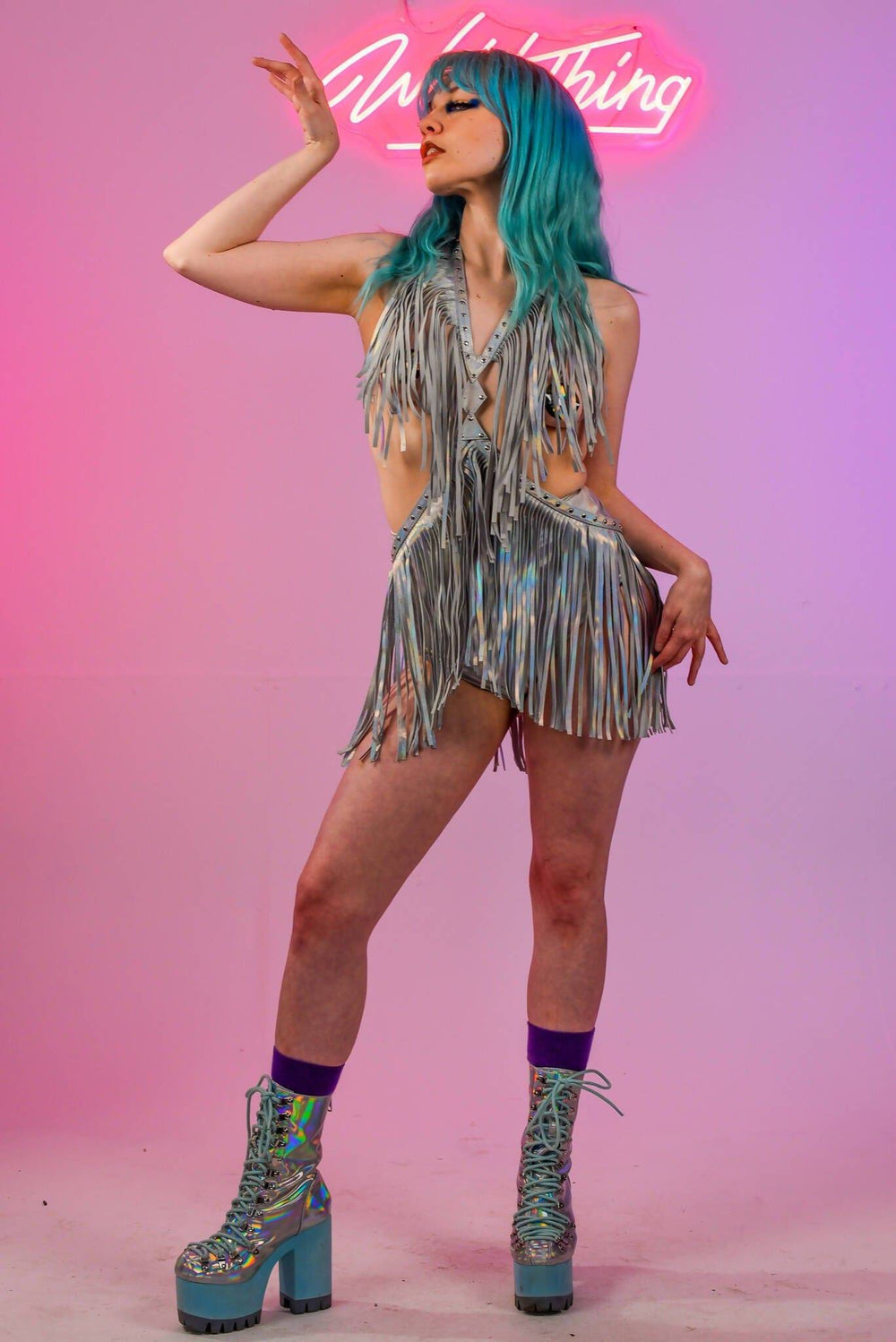 Model posing in holographic silver fringe harness dress, side view.