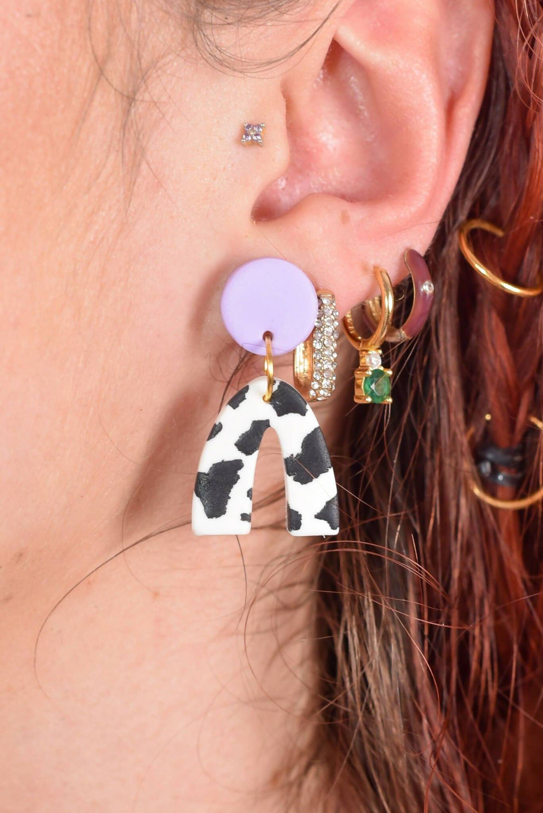 Close-up of polymer clay cow print mini arch earring