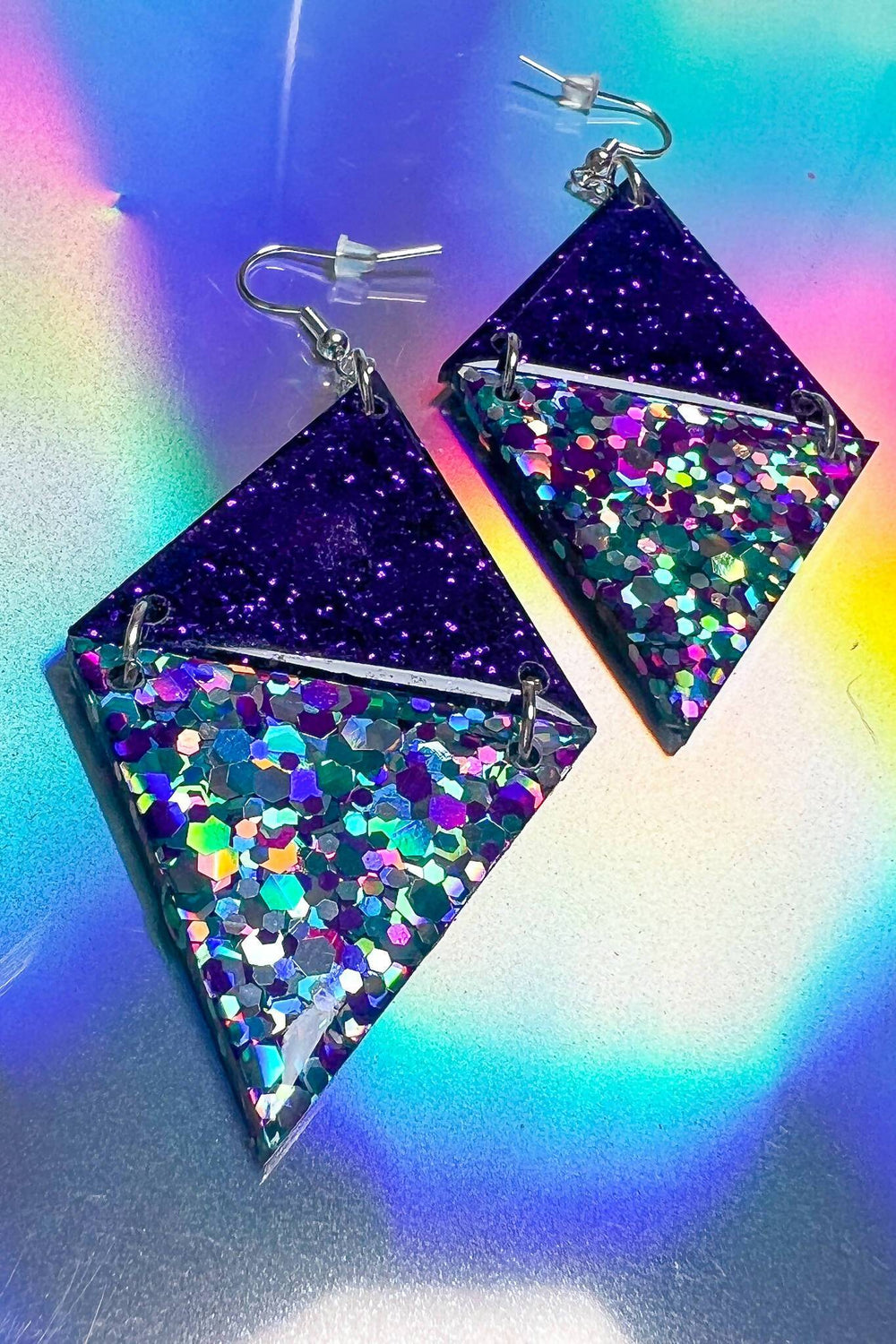 Purple glitter triangle earrings with rainbow resin on holographic background